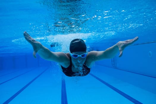 Female swimmer diving underwater in swimming pool