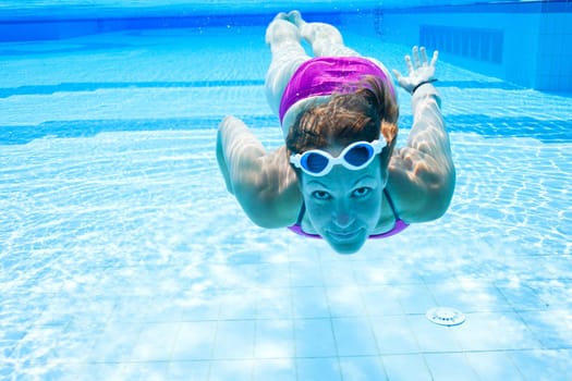 Female swimmer underwater in swimming pool with eyes open