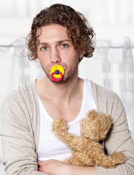 Portrait of a young man with a pacifier and teddy bear,isolated on white
