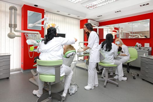 Dentists at work in modern red dental office