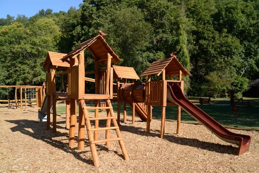 Wooden playground equipment with slides at summer time.