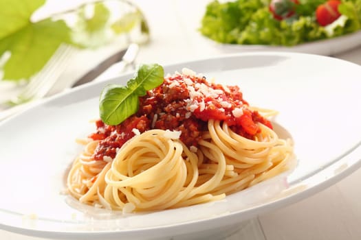 Close up low angle view of a plate of twirled spaghetti topped with delicious bolognaise sauce and basil