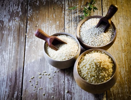 High angle view of three earthenware rustic pots containing dried bulgur and couscous made from crushed durum and semolina wheat and quinoa seeds, a high-protein staple of the goosefoot family