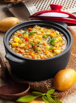 Delicious lentil and vegetable stew in a rustic kitchen in an open crock, high angle view
