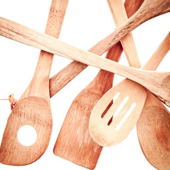 Close up jumbled array of wooden kitchen utensils isolated on a white background