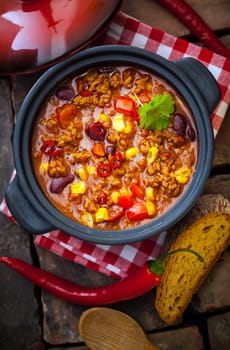 Overhead view of a pot of colourful, rich lentil and vegetable stew with peppers, corn, carrots and lentils in a ountry kitchen