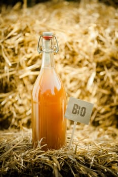Close-up of a bottle of organic natural homemade juice, tagged as 'bio' product on straw