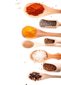 Overhead view of wooden scoops and spoons in different shapes and sizes filled with assorted spices and condiments isolated on white with copyspace