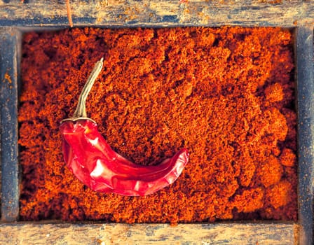 Colourful red chilli powder with a dried cayenne chilli pepper, a strong pungent spice with a hot flavour used as a seasoning and flavouring in cookery