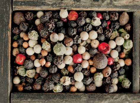 Overhead view of assorted mixed peppercorns with whole dried black, white and red or pink peppercorns used as a hot pungent spice and condiment