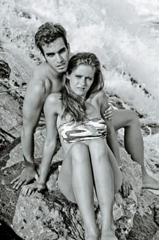 Romantic couple next to river waterfall, naked, wearing swimming suit and bikini