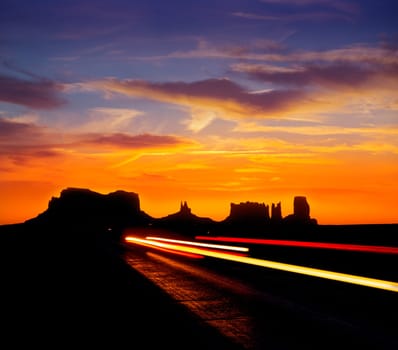 Sunrise on US 163 Scenic road to Monument Valley Park with car headlights Utah