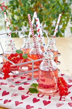 Fresh lemonade in small bottles with red currants