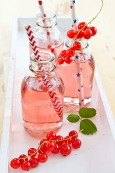 Fresh lemonade in small bottles with red currants