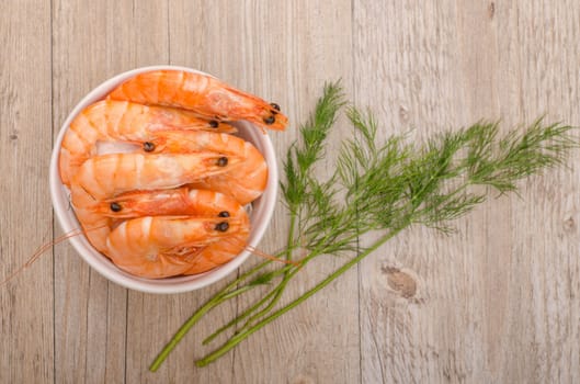 Cooked prawns and dill on a wooden table