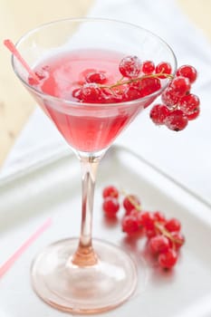 Red cocktail in a stem jar with fresh currants