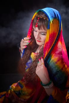 A mature woman models a beautifully colored sari while gracefully posing and showcasing Indian cultural elements in a chic setting.