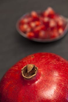 Close-up of a juicy ripe pomegranate,blurred in the background a spoonful of pomegranate seeds