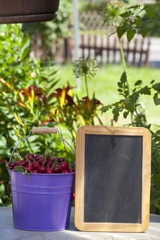 Tin bucket with cherries and a blank writable slate
