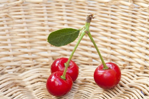 Three cherries with stem and leaf in the basket