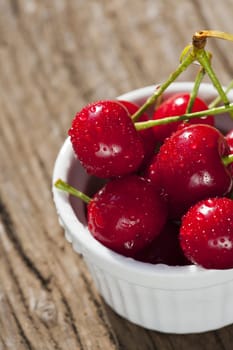 Bowl of ripe cherries on wooden table