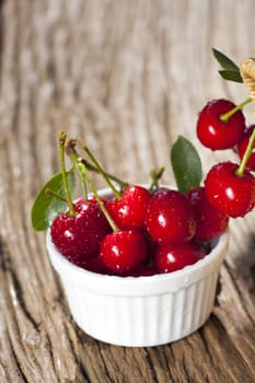 Bowl of cherries stands on rustic wooden table