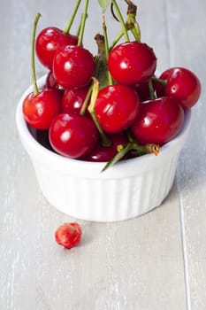 Bowl with cherries and a cherry pit in front of it