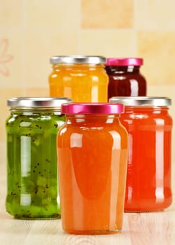 Jars of fruity jams on kitchen table. Preserved fruits