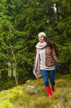 Woman walking in pinewood autumn wear knitted scarf and hat