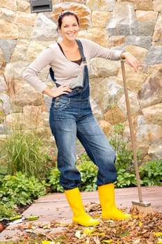 Young woman sweeping autumn leaves garden smiling cleaning backyard fall