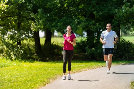 Caucasian boyfriend and girlfriend running a race in sunny park