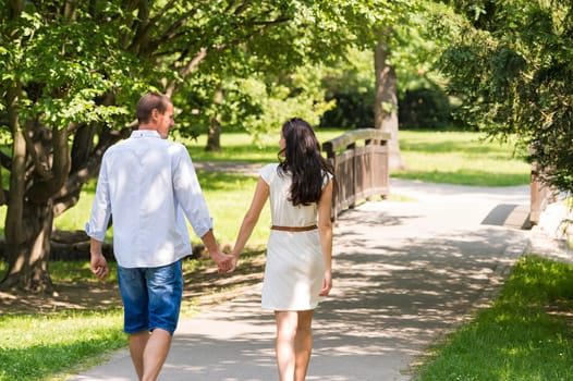 Rear view of walking caucasian couple in park