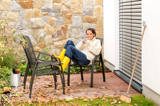 Happy woman relaxing autumn housework drinking coffee fall patio
