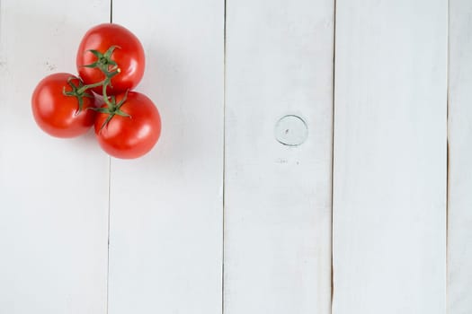 Three tomatoes over a white wooden background