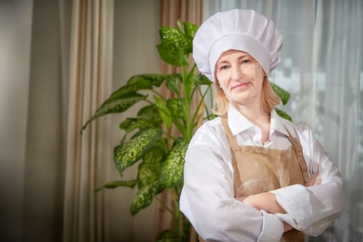 An elderly woman playfully poses as a cook, showcasing her flour preparations in a warm, inviting kitchen atmosphere.