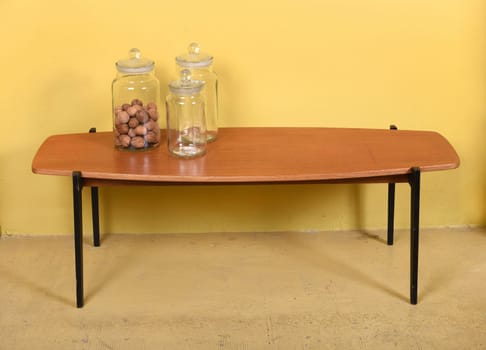 Furniture Still Life of Retro Coffee Table with Collection of Three Glass Jars - One with Nuts - in Room with Yellow Walls