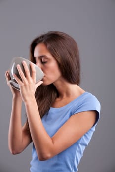 Beautiful young woman drinking from a mugful for breakfast