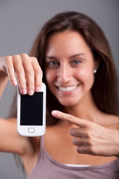 Close-up of a Young Woman holding out a phone pointing out a blank screen while watching at you