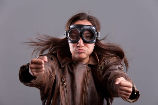 Funny girl with motorbiker big glasses and a leather jacket pretending to blow