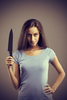 Unsettling dark young woman holding a dengerous knife in his hand