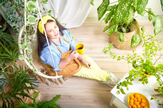 A gardener relaxes with a cup in hand, surrounded by lush greenery and blooming flowers.