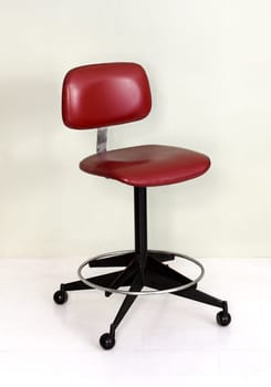 Furniture Still Life of Vintage Office Chair with Red Seat and Wheel Casters in Room with White Background and Floor
