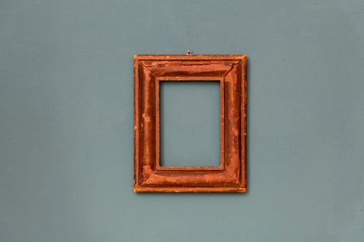 Small moulded rectangular vintage wooden frame hanging in the center on a teal colored wall
