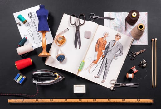 Selection of tools for a tailor or seamstress with retro patterns, iron, scissors, tape measure, yarn, needles and a ruler displayed on a black background