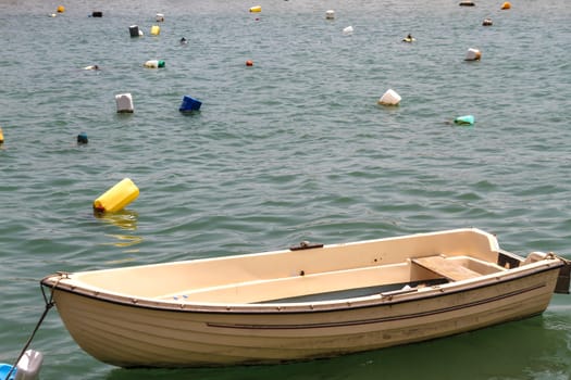 Wooden rowboat in the sea surrounded by plastic containers.