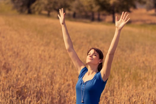 Enjoying sun in nature with hands up. The blue of the dress is the only blue in the picture - perfect for coloration.