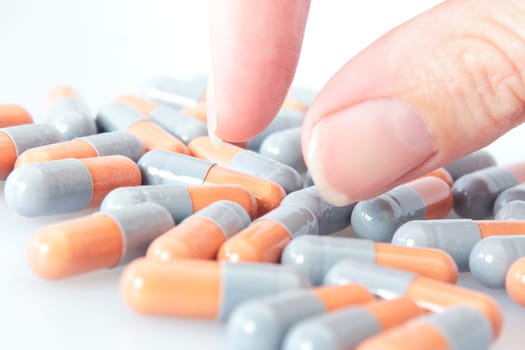 close up of many tablets with a thumb and finger reaching to pick one up