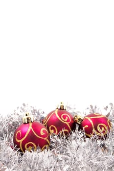 red and gold christmas baubles on a bed of silver tinsel with copy space at the top