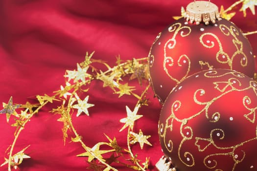 Two red christmas bulbs with gold  chain on a red background