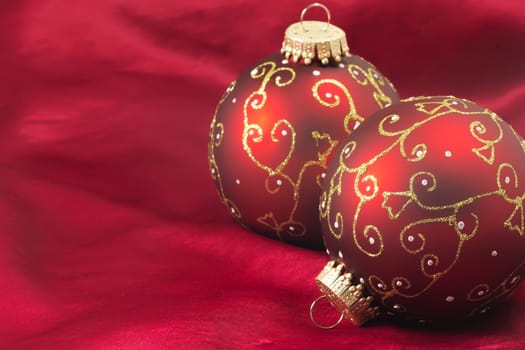 Two red christmas bulbs on a red background